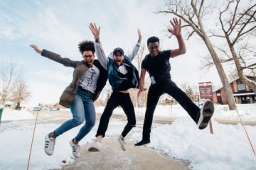 3 happy students jumping in snow