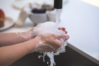 adult washing hands with water
